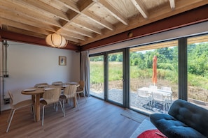 Un intérieur moderne comprenant un coin repas, un canapé et de grandes fenêtres donnant sur l’extérieur.