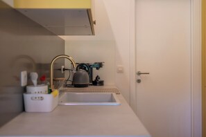 Une cuisine compacte équipée d’un évier, d’une bouilloire et d’une machine à café.