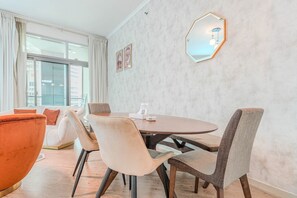 Ein modernes Hotelzimmer mit einem runden Esstisch, zwei Stühlen, einer Couch und einem großen Spiegel an der Wand.