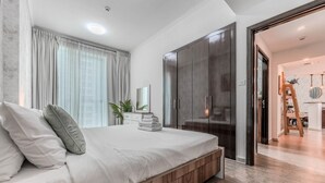 Ein modernes Schlafzimmer mit einem großen Bett, einem Kleiderschrank und Blick in den Wohnbereich.