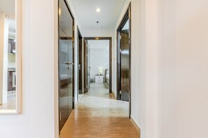 A hallway with a wooden floor leading to a bedroom with a bed and a nightstand. - HAVN - 2 Bed in Dubai Marina, 5 mins to Tram (Dubai)