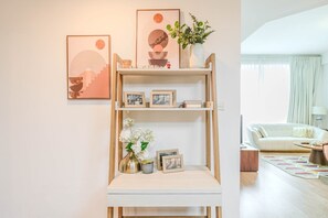 A living room with a white sofa, a coffee table, and a bookshelf with framed pictures and decorative items. - HAVN - 2 Bed in Dubai Marina, 5 mins to Tram (Dubai)