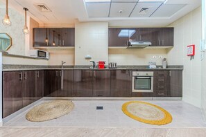 A modern kitchen with dark wood cabinets, a microwave, a toaster, and a built-in oven. - HAVN - 2 Bed in Dubai Marina, 5 mins to Tram (Dubai)