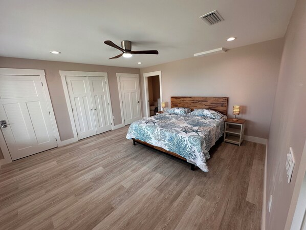 A bedroom with a bed, a ceiling fan, and a nightstand with a lamp.