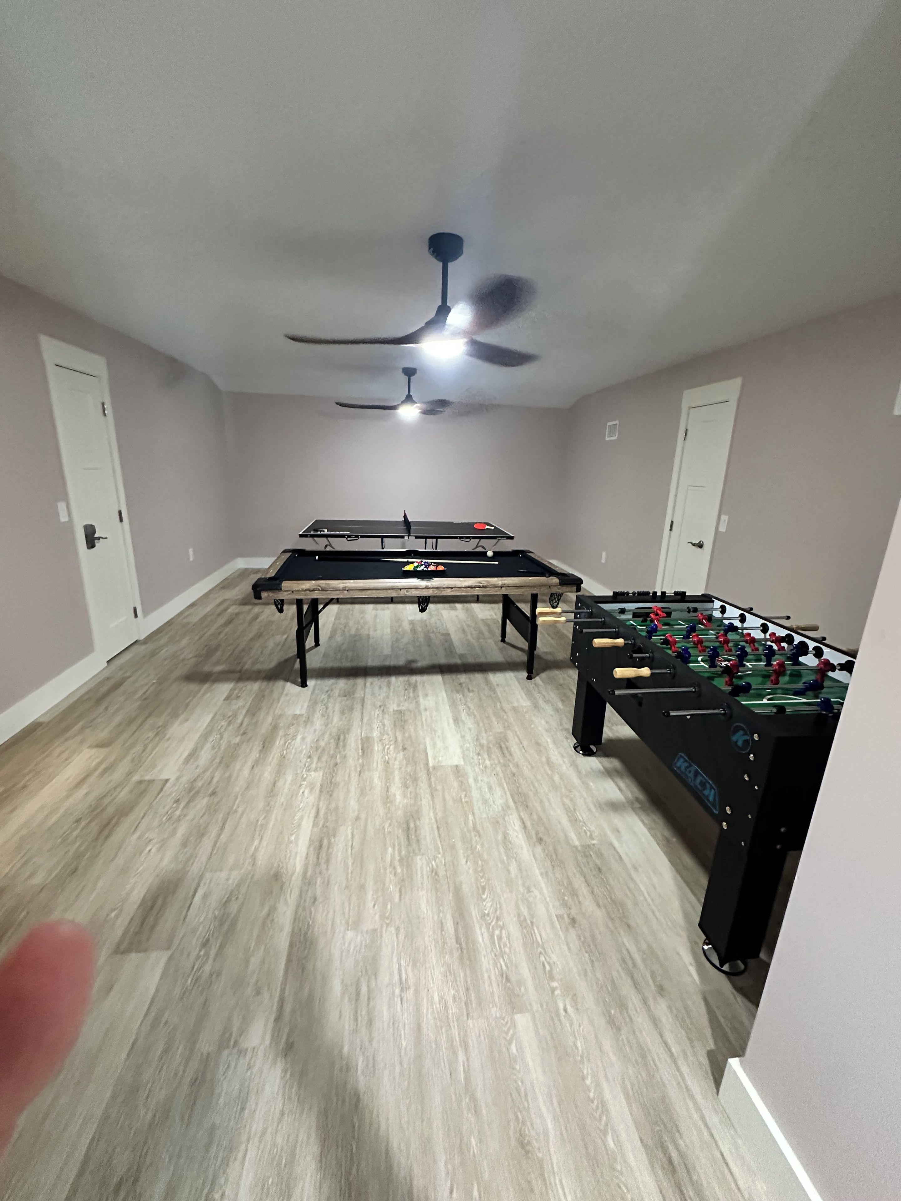 Une pièce équipée d’un baby-foot et d’une table de ping-pong, d’un ventilateur de plafond et d’un luminaire.