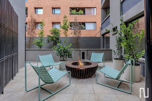 A rooftop patio with two green metal chairs, a central fire pit, and potted plants. - NOK Comfortable 3BR Apartment in North Bogota (Bogotá)