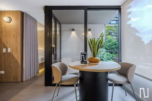 Uma sala de jantar moderna com uma mesa redonda, duas cadeiras, um vaso de planta e um armário de madeira.