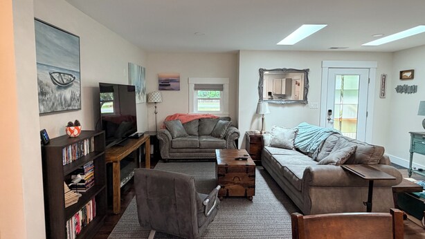 A living room with a sofa, armchair, and a television on a wooden stand. - Beach Wolf: ALL NEW, impeccable house in Southern Shores, 5 minute walk to beach (Kitty Hawk)