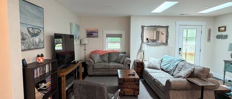 A living room with a sofa, armchair, and a television on a wooden stand.