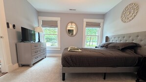 A bedroom with a bed, dresser, TV, and two windows. - Beach Wolf: ALL NEW, impeccable house in Southern Shores, 5 minute walk to beach (Kitty Hawk)