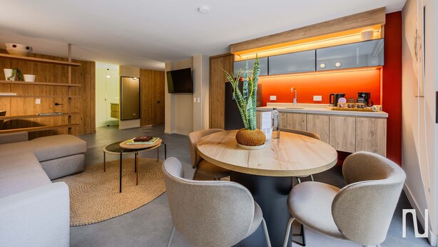 A modern kitchen with a red accent wall, a round dining table with chairs, and a wooden buffet. - NOK Spacious 3BR Apartment Near Zona T, Bogota (Bogotá)