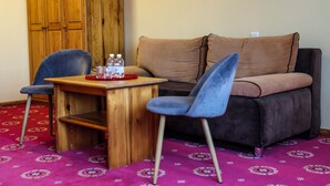 Una habitación con una mesa de madera, dos sillas, un sofá y una alfombra estampada.