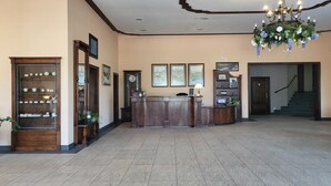 Un área de recepción con mostrador de madera, obras de arte enmarcadas en las paredes y un candelabro.
