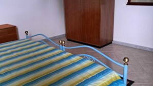 A bedroom with a bed, a wardrobe, and a mirror on the wall. - Casa Rurale - S'Olivare di Filieri (Dorgali)