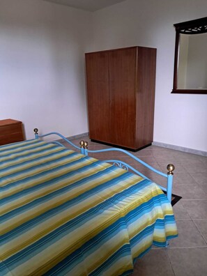 Ein Schlafzimmer mit Bett, Kleiderschrank und Spiegel an der Wand.