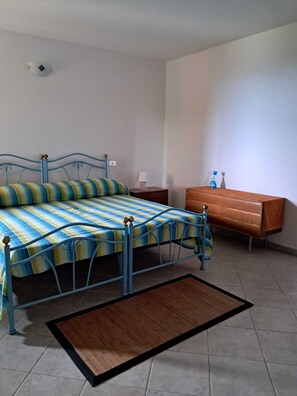 A bedroom with a bed, a nightstand, a dresser, and a small rug. - Casa Rurale - S'Olivare di Filieri (Dorgali)
