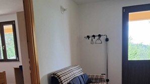 A room with a sofa, a floor lamp, a door, and a window. - Casa Rurale - S'Olivare di Filieri (Dorgali)