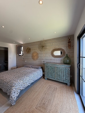 A bedroom with a bed, a dresser, a mirror, and a window. - Vacation Home for Rent (Belgodère)