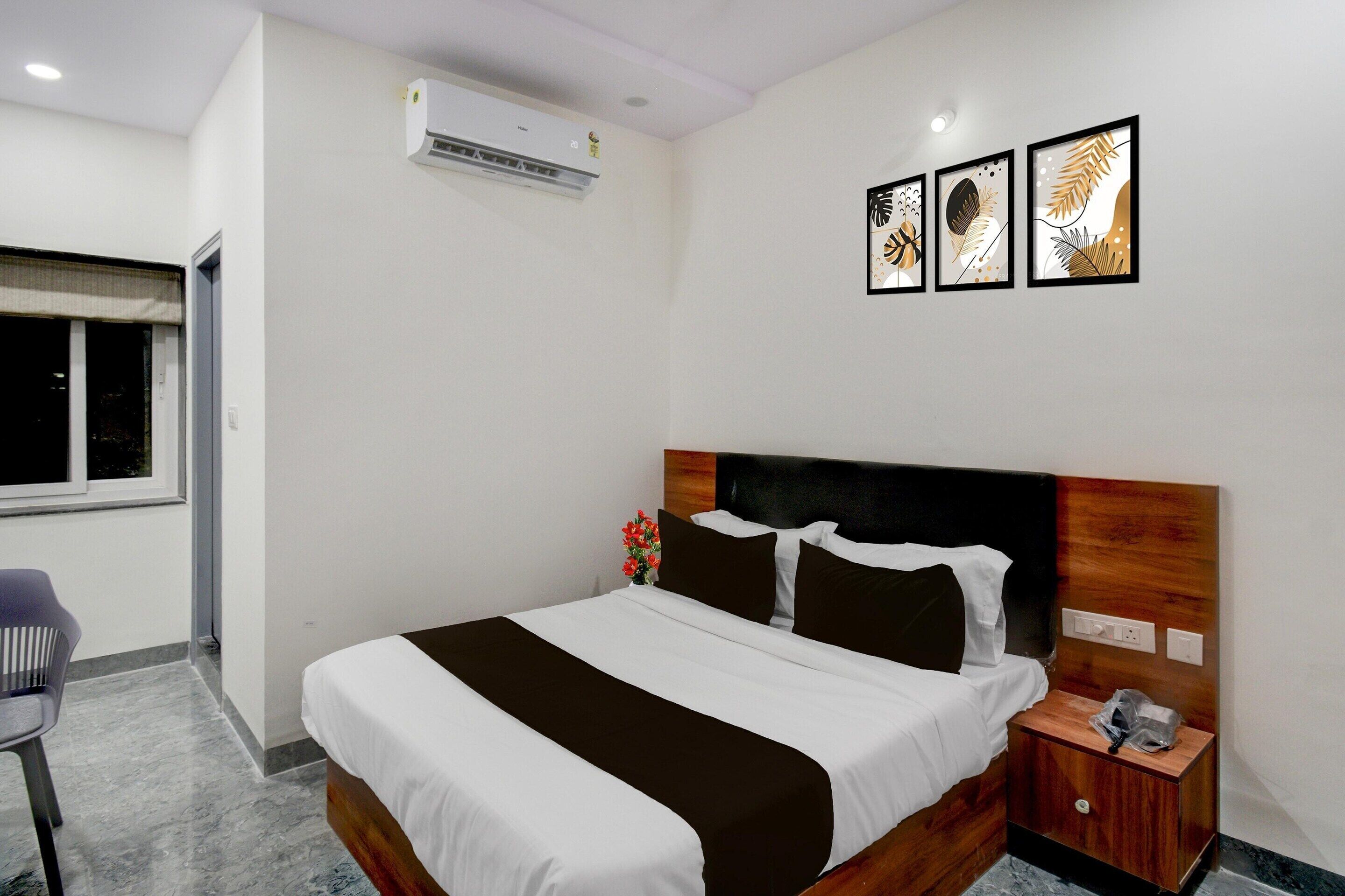 A hotel room with a bed, a nightstand, a chair, a window, and wall art.