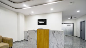 Un mostrador de recepción con un letrero, un sofá y un suelo de mármol.
