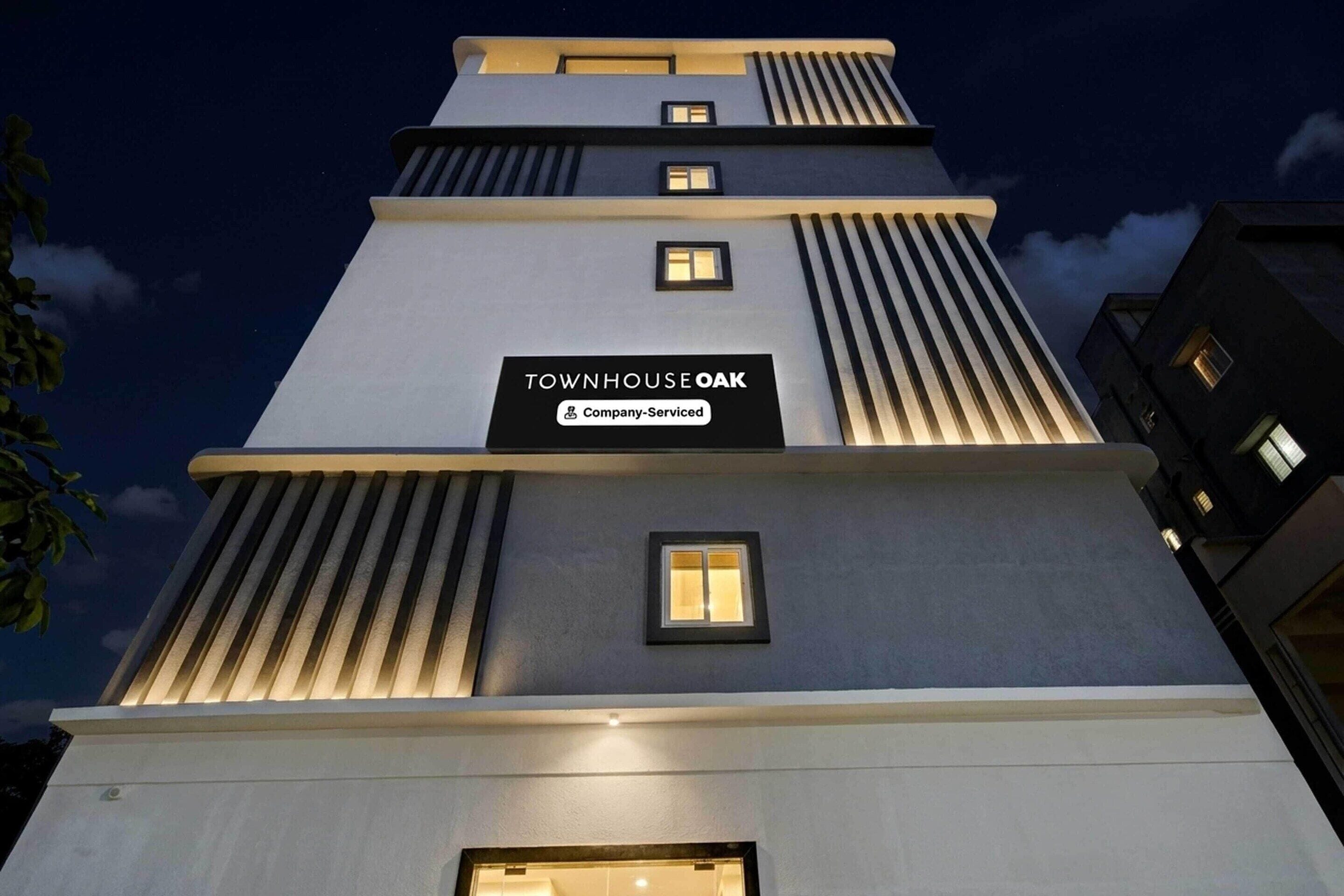 A multi-story building with a sign reading 'TOWNHOUSE OAK' and a company-serviced label.