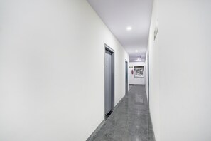A corridor with white walls, a grey floor, and a door at the end. - Deluxe Townhouse Saroornagar (Hyderabad)