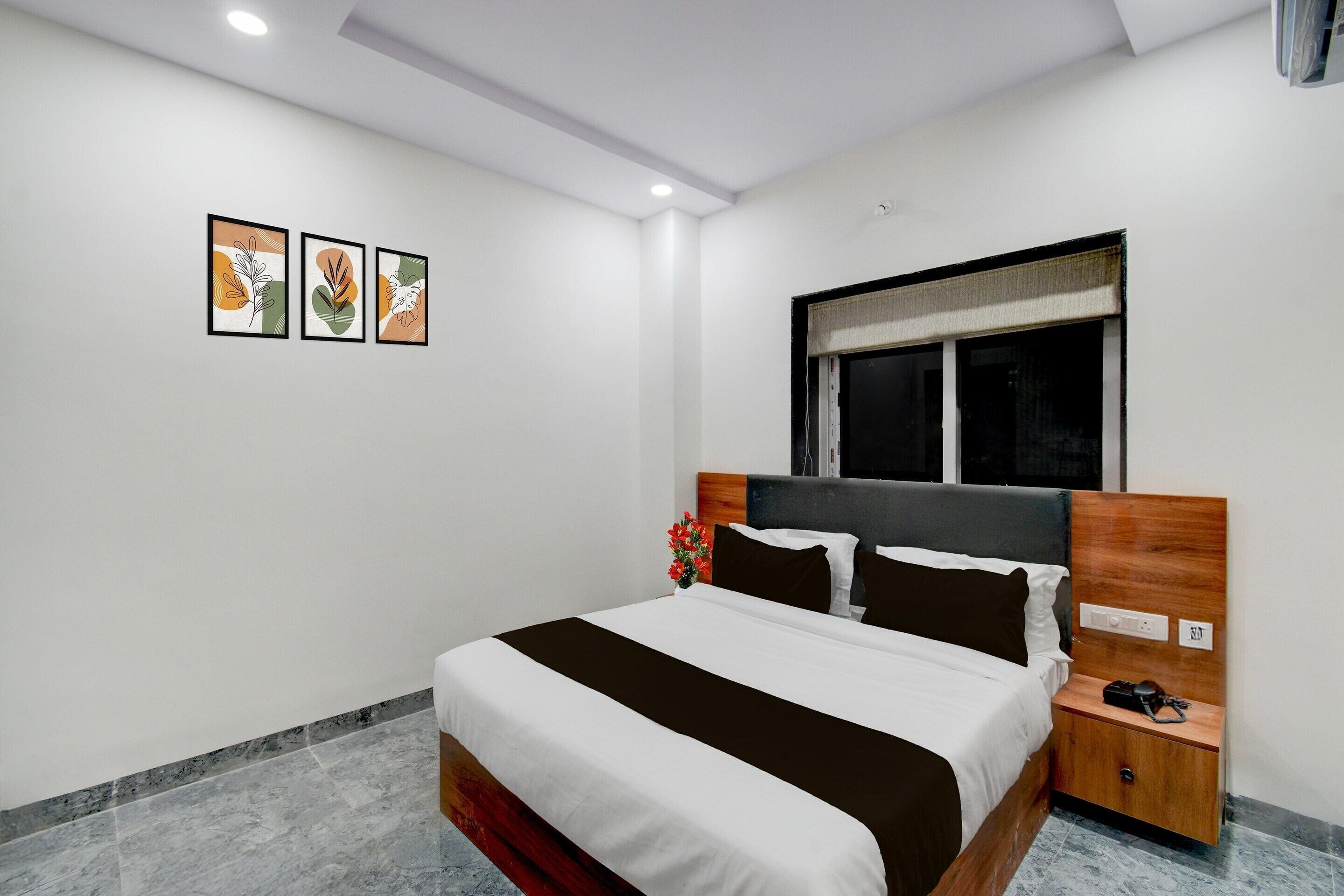 Quarto de hotel moderno com uma cama grande, uma mesa de cabeceira, uma janela com vista e três obras de arte emolduradas na parede.