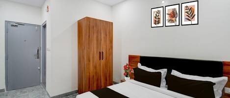 A hotel room with a bed, wardrobe, and artwork on the wall.