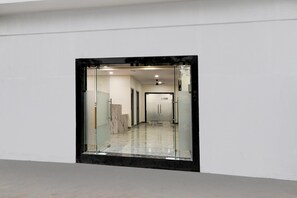 A hallway with a glass wall, a ceiling fan, and a marble floor. - Deluxe Townhouse Saroornagar (Hyderabad)