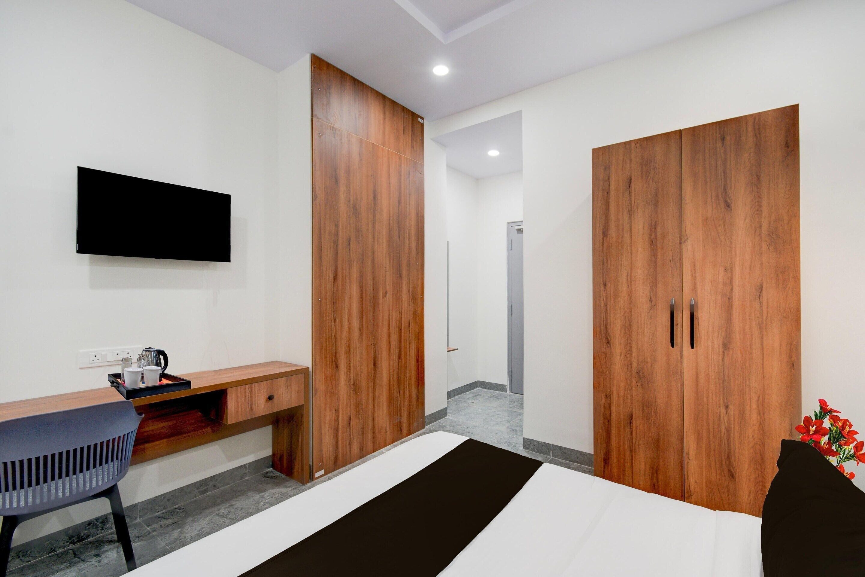 A modern bedroom with a bed, a desk, a chair, a wardrobe, and a TV.