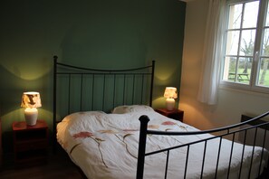 En säng för en person med en metallram, två sängbord med lampor och ett fönster med utsikt över omgivningen.