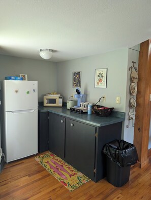 A compact kitchen with a refrigerator, microwave, and a coffee maker on the counter.
