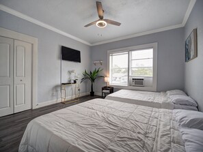 A bedroom with two beds, a ceiling fan, a TV, a window with blinds, and a plant. - 2-bedroom 1-bathroom apt (Tampa)