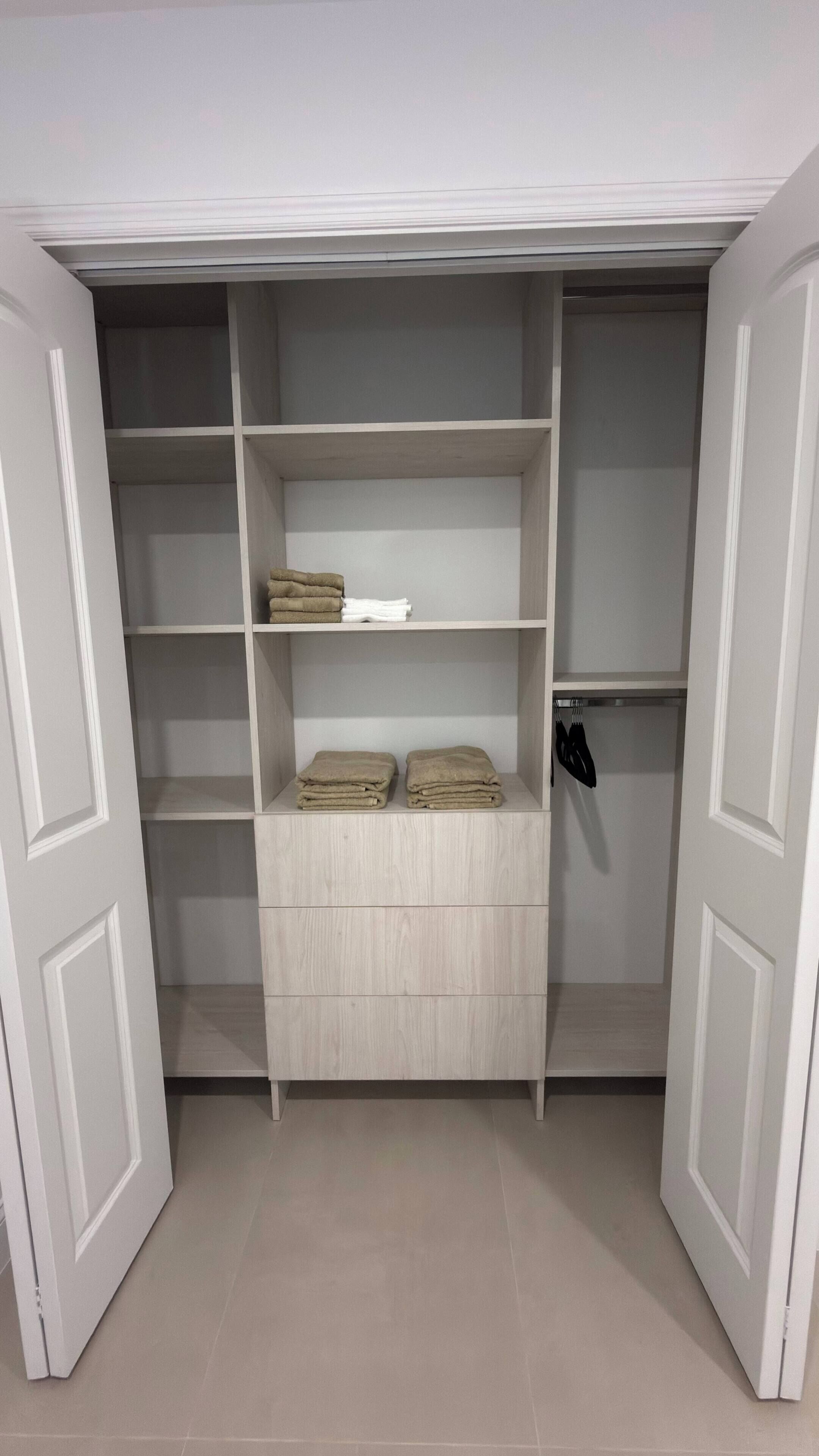 Um closet amplo com várias prateleiras e gavetas, algumas contendo toalhas dobradas.