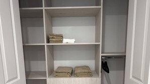 A walk-in closet with multiple shelves and drawers, some containing folded towels.