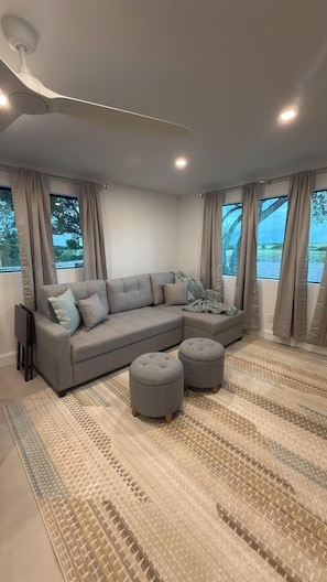 A modern living room with a sectional sofa, ottomans, and a patterned rug. - Beautiful 4-Bedroom Retreat in Sebring, Close to the Racetrack (Sebring)