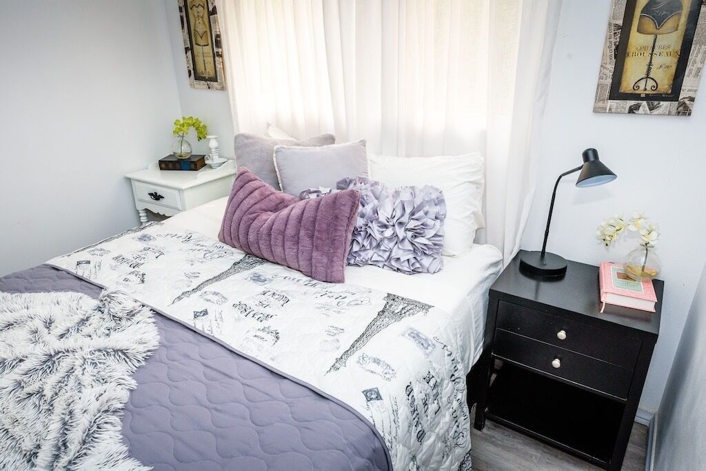 A neatly made bed with a patterned bedspread, a fluffy throw blanket, and decorative pillows.