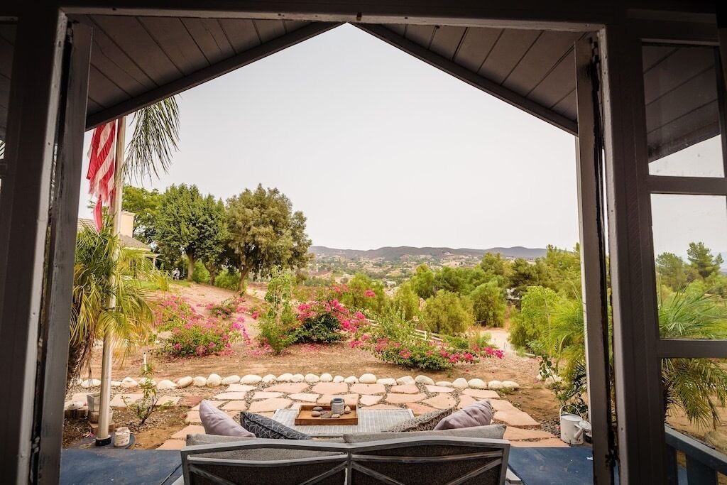 An outdoor seating area with a view of a landscaped garden and distant hills.