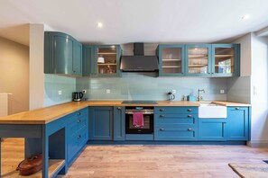 Una cocina moderna con gabinetes color verde azulado, una campana extractora de acero inoxidable y un horno empotrado.
