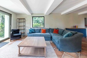 Ein modernes Wohnzimmer mit einer Eckcouch, einem Couchtisch und einem Bücherregal.