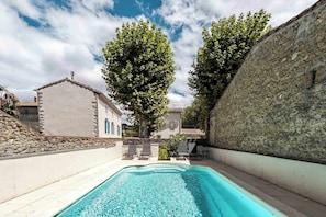 A swimming pool with a stone wall on one side and a building with a sloped roof on the other. - Mill near Carcassonne, with a pool and river (Bouilhonnac)