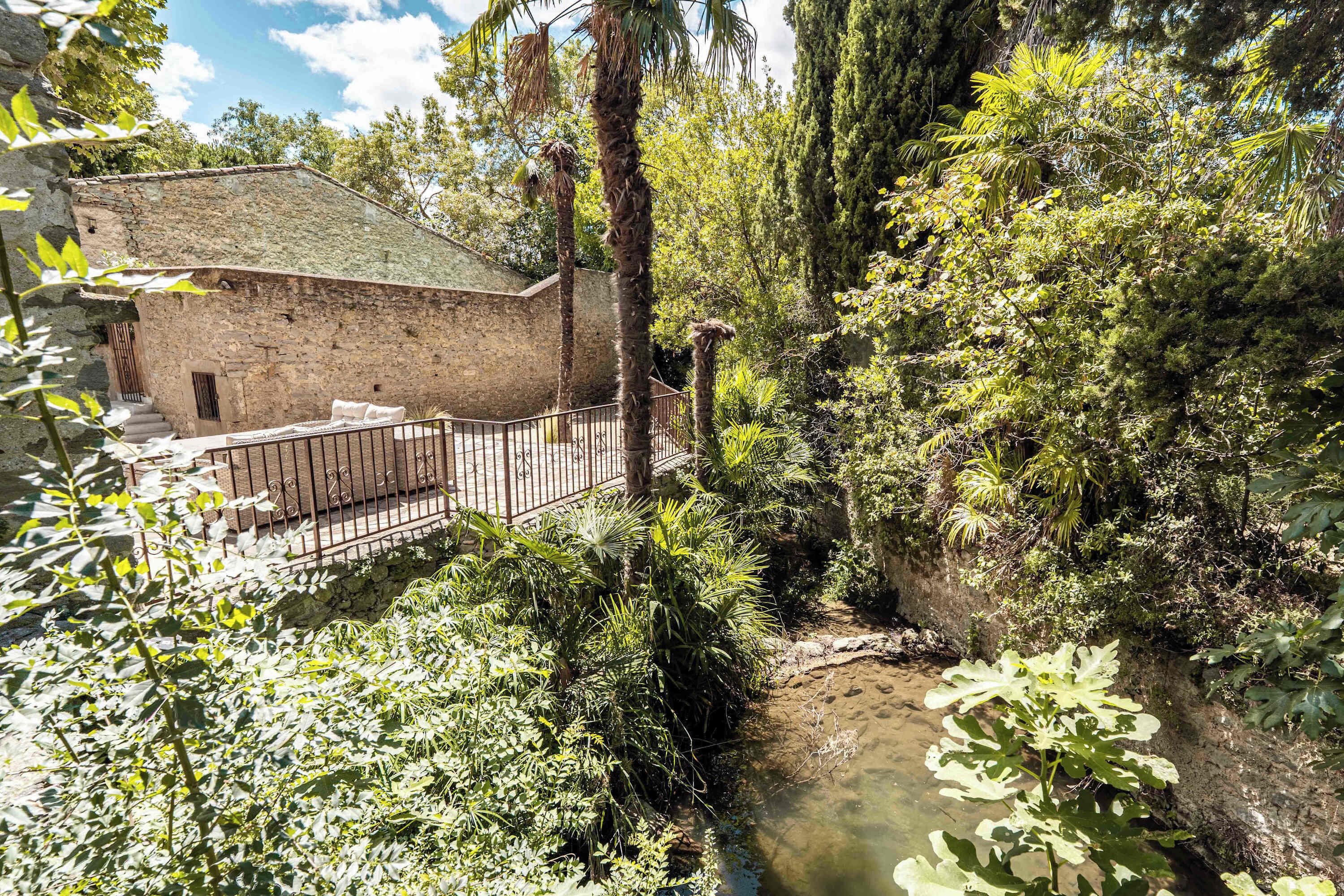 A stone building with a metal fence and a narrow water channel.