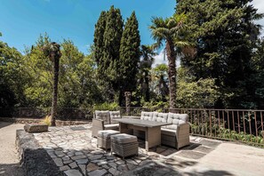 An outdoor patio with a stone floor, wicker furniture, and a metal fence. - Mill near Carcassonne, with a pool and river (Bouilhonnac)