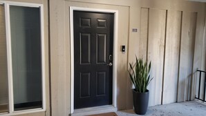 A black door with a white frame, a potted plant beside it, and a number '251' sign on the wall. - Gainesville 2BR/2BA Comfort Stay (Gainesville)