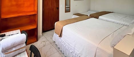 A hotel room with a bed, a desk with a keyboard, a chair, a wardrobe, and a television on the wall.