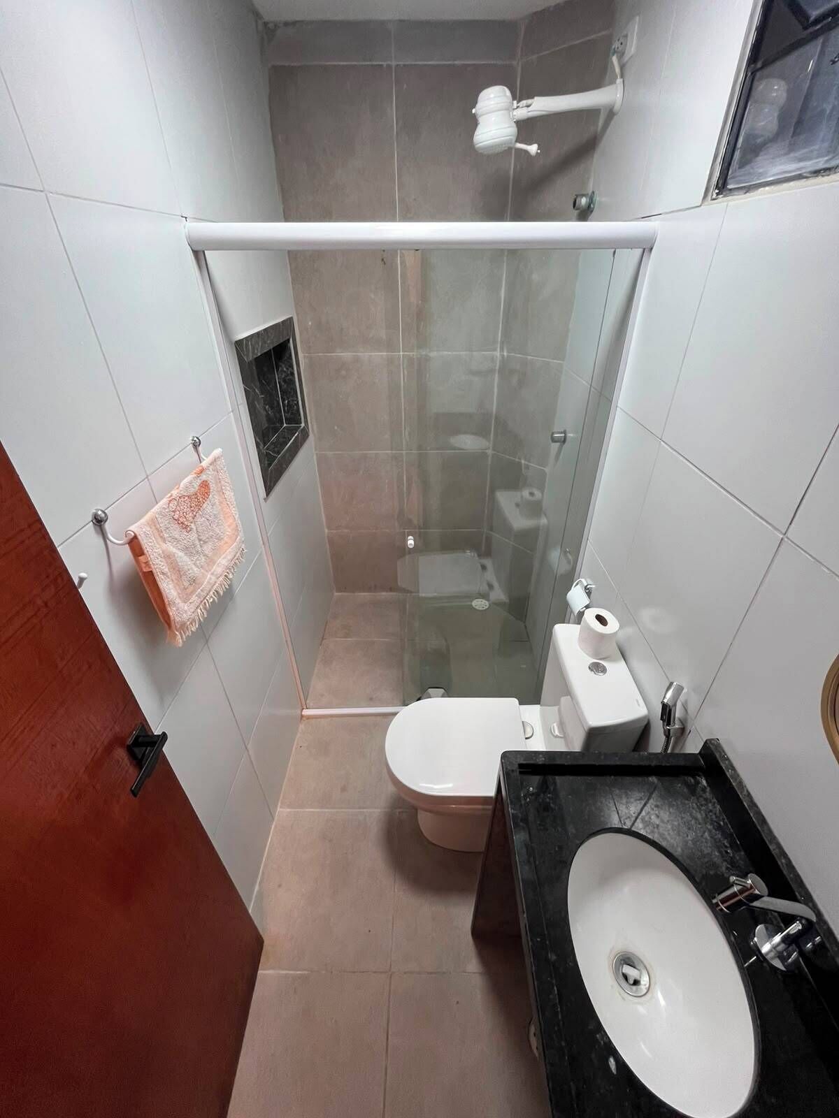 Un bagno compatto con doccia vetrata, un water e un lavandino.