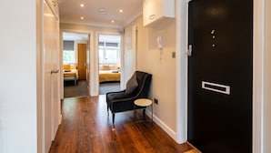 A hallway with a black door, a black leather chair, and a small round table. - Top-Floor 3-Bed Flat Sleeps 6 · Free Parking · Walk to Clissold Park (Greater London)