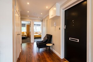 A hallway with a black door, a black leather chair, and a small round table. - Top-Floor 3-Bed Flat Sleeps 6 · Free Parking · Walk to Clissold Park (Greater London)