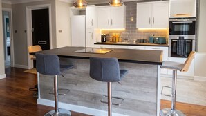 A modern kitchen with a central island, bar stools, pendant lighting, and stainless steel appliances. - Top-Floor 3-Bed Flat Sleeps 6 · Free Parking · Walk to Clissold Park (Greater London)