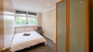 A bedroom with a bed, a window, a wardrobe, and a chair. - Top-Floor 3-Bed Flat Sleeps 6 · Free Parking · Walk to Clissold Park (Greater London)